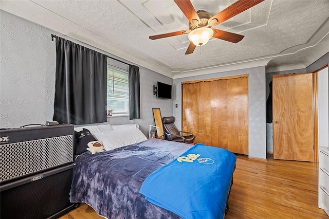426 Oliver Dr, White Oak, PA 15131 - bedroom featuring a textured ceiling, wood finished floors, a closet, a ceiling fan, and wallpapered walls