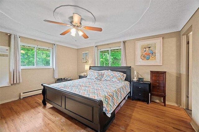 426 Oliver Dr, White Oak, PA 15131 - bedroom featuring a baseboard heating unit, wood finished floors, baseboards, and ceiling fan