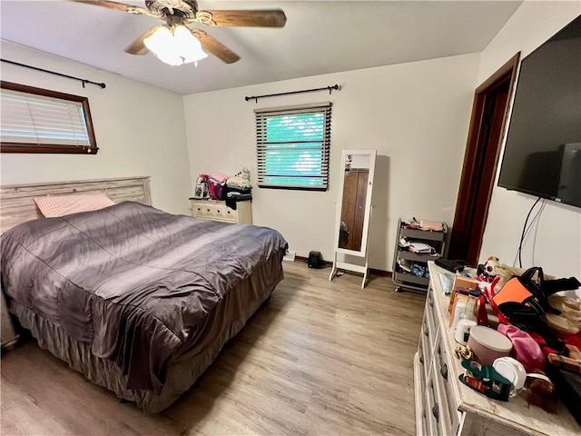 bedroom with light wood-style floors, baseboards, and a ceiling fan