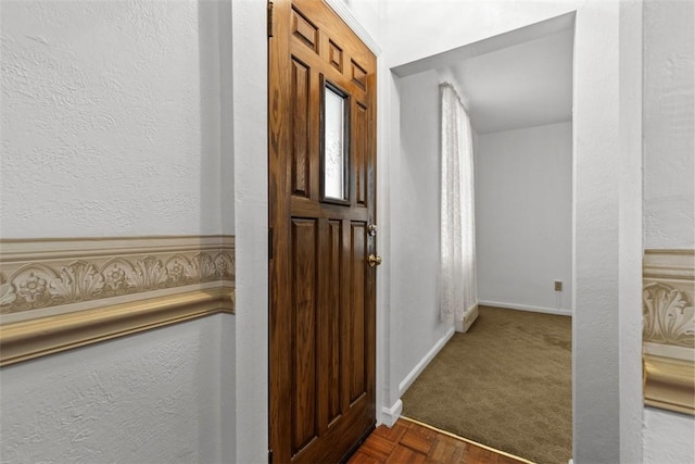 foyer entrance with baseboards and a textured wall