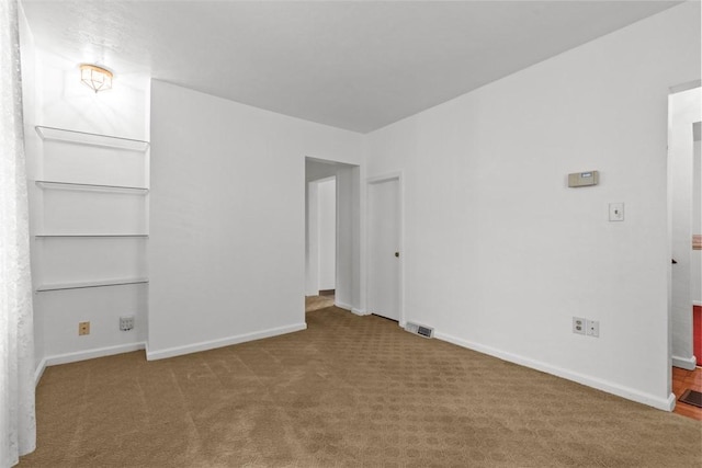 carpeted empty room featuring baseboards