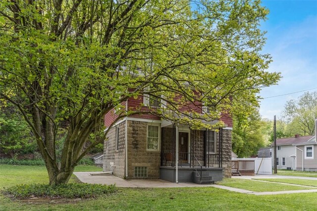 rear view of property with stone siding, a yard, and central AC unit