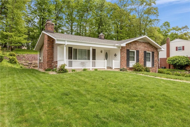 ranch-style house featuring a chimney, covered porch, brick siding, and a front lawn