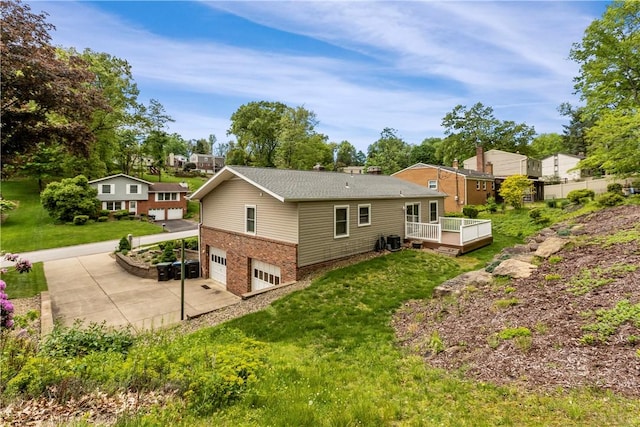 rear view of house with a garage, brick siding, a wooden deck, driveway, and a lawn