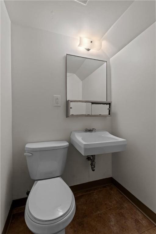half bathroom featuring baseboards and toilet