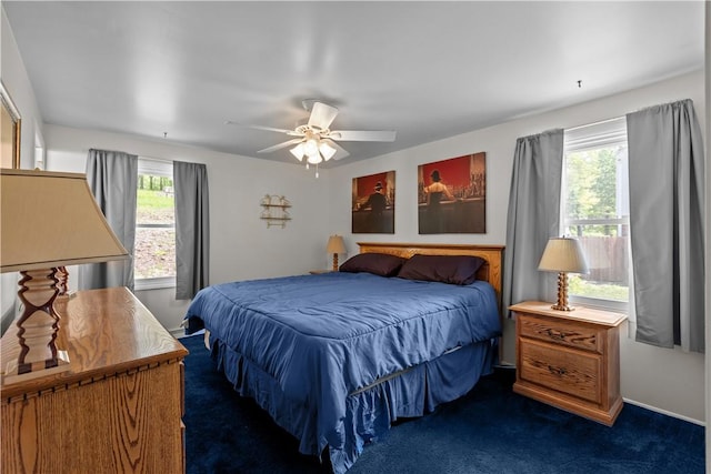 bedroom with multiple windows, dark colored carpet, and ceiling fan