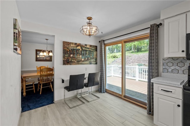 dining area with a chandelier, light wood-type flooring, and baseboards