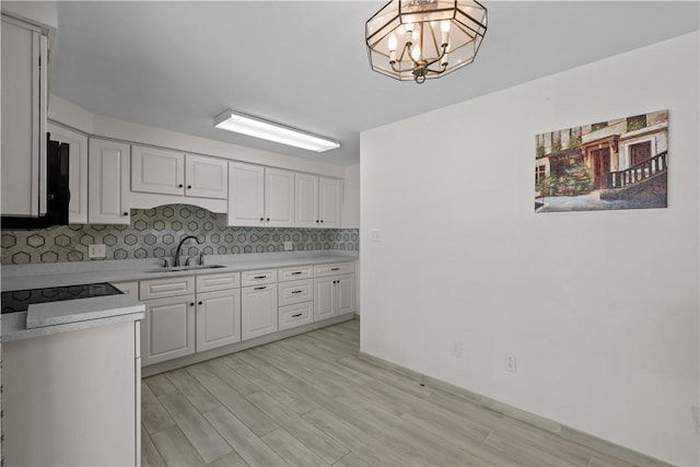 kitchen featuring a sink, light countertops, white cabinets, and tasteful backsplash