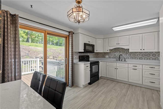 kitchen featuring black appliances, a sink, light countertops, and light wood-style floors