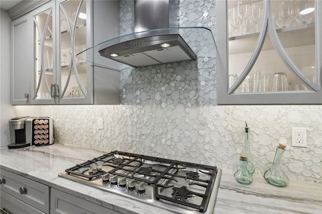 1231 Nicklaus Way W, Deer, PA 15044 - kitchen with wall chimney exhaust hood, stainless steel gas cooktop, gray cabinets, decorative backsplash, and glass insert cabinets
