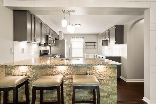 239 Mountain Dr, Carnegie, PA 15106 - kitchen featuring appliances with stainless steel finishes, a peninsula, a sink, dark wood-type flooring, and light stone countertops