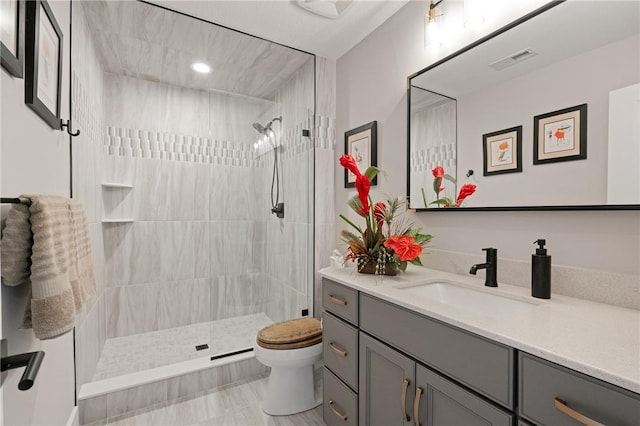 bathroom featuring vanity, toilet, and tiled shower