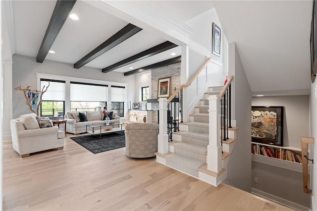 living area with healthy amount of natural light, light wood-style floors, beam ceiling, stairway, and recessed lighting