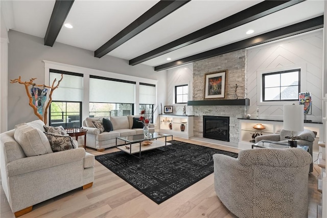 living room featuring beamed ceiling, light wood-style flooring, and a fireplace