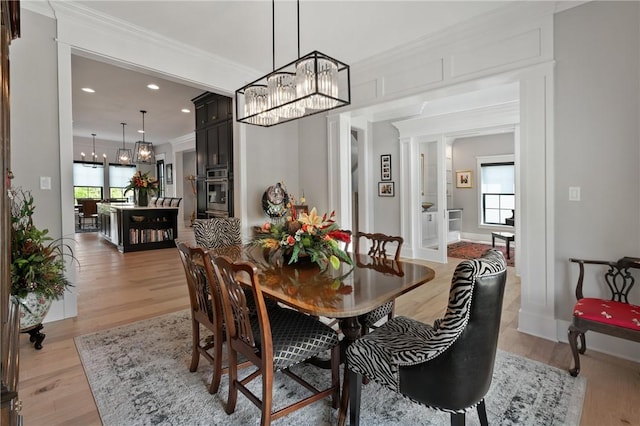 dining area with a chandelier, light wood finished floors, crown molding, recessed lighting, and baseboards