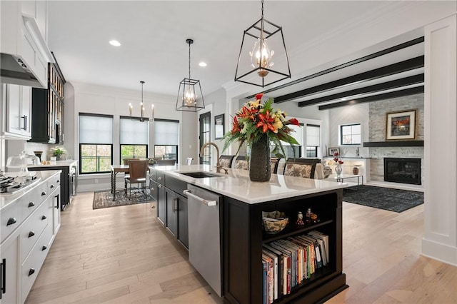 kitchen with appliances with stainless steel finishes, a sink, a chandelier, light countertops, and hanging light fixtures