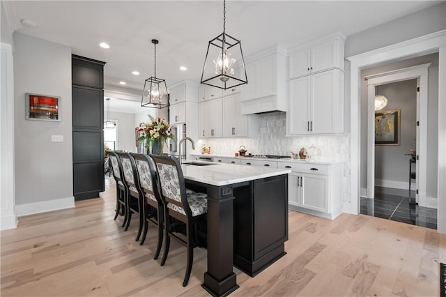 kitchen with a sink, baseboards, backsplash, light wood-style flooring, and recessed lighting