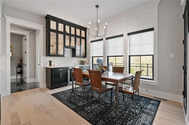 dining room with baseboards, a chandelier, and light wood-type flooring