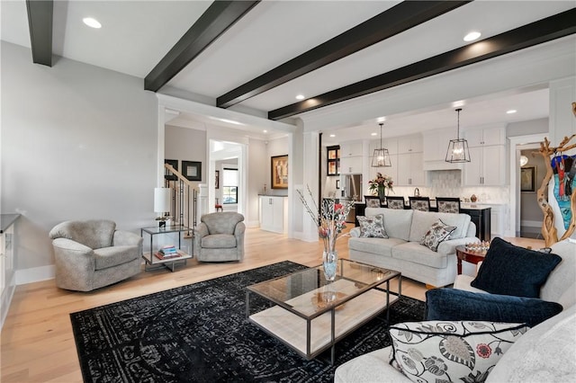 living area with beam ceiling, light wood finished floors, stairway, recessed lighting, and baseboards