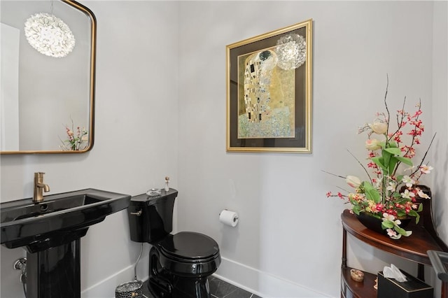 half bath featuring baseboards, toilet, tile patterned floors, and a sink