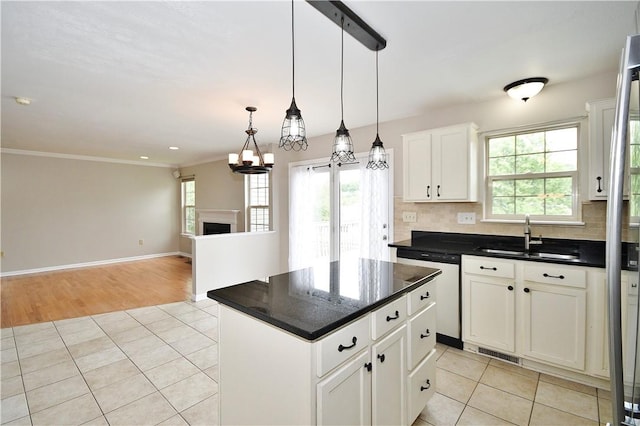 kitchen with a sink, dishwasher, light tile patterned floors, a center island, and ornamental molding