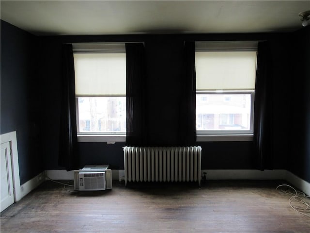spare room with radiator heating unit, plenty of natural light, and wood finished floors