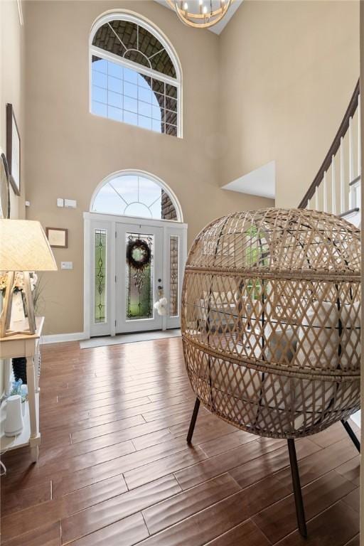 foyer featuring a high ceiling, hardwood / wood-style floors, a chandelier, and baseboards