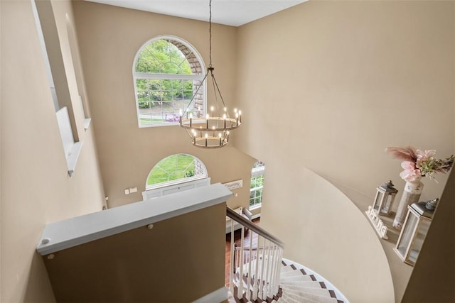 stairway featuring a chandelier, plenty of natural light, and a towering ceiling