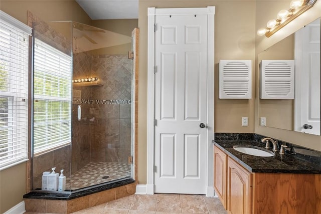full bath featuring a shower stall, vanity, tile patterned flooring, and baseboards