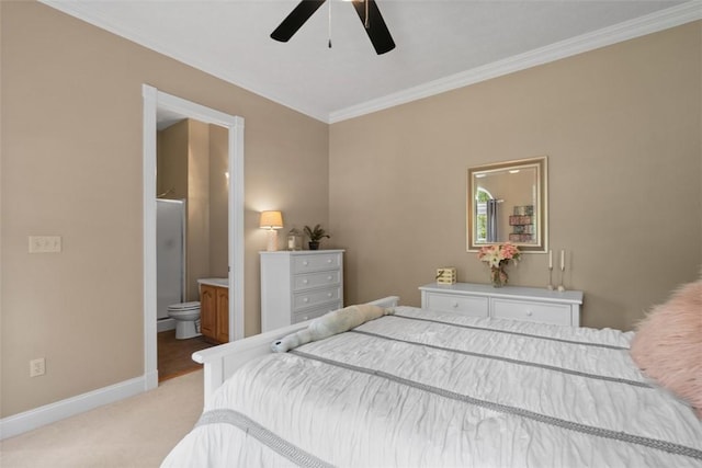 bedroom featuring crown molding, baseboards, light colored carpet, ensuite bath, and a ceiling fan
