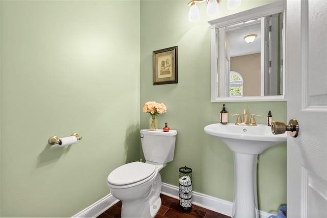 half bathroom featuring toilet, baseboards, and wood finished floors