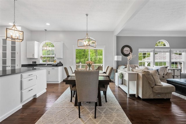 dining area featuring a chandelier, dark wood-type flooring, recessed lighting, a textured ceiling, and beamed ceiling