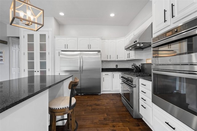 kitchen featuring stainless steel appliances, wall chimney range hood, white cabinetry, dark wood-type flooring, and recessed lighting