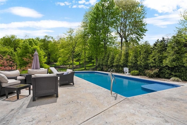 outdoor pool with a patio area, outdoor lounge area, and a wooded view