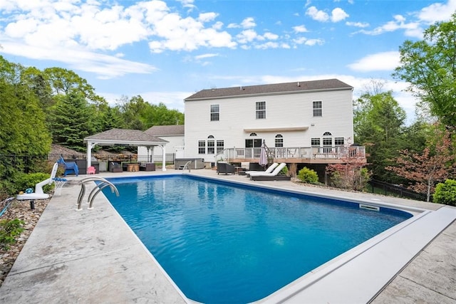 outdoor pool with a gazebo, a wooden deck, fence, and a patio