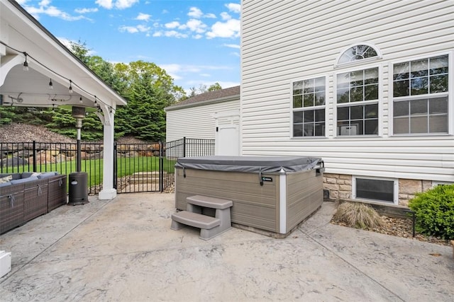 view of patio / terrace with a hot tub and fence