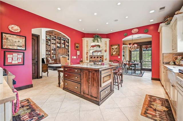 kitchen featuring a chandelier, recessed lighting, a kitchen bar, stainless steel microwave, and light tile patterned floors