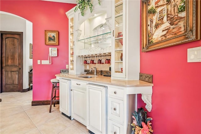 indoor wet bar featuring light tile patterned floors and arched walkways