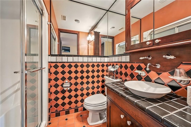 full bath with tile patterned flooring, a shower stall, vanity, toilet, and tile walls