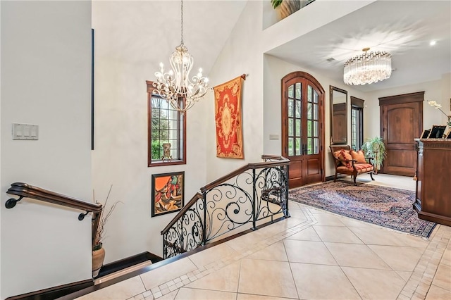 tiled entrance foyer with a chandelier, high vaulted ceiling, inlaid floor details, and baseboards