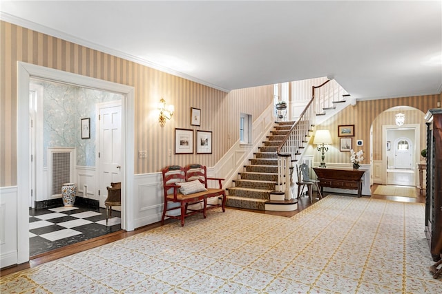 265 Scaife Rd, Sewickley Heights, PA 15143 - foyer featuring crown molding, stairs, a decorative wall, a wainscoted wall, and arched walkways