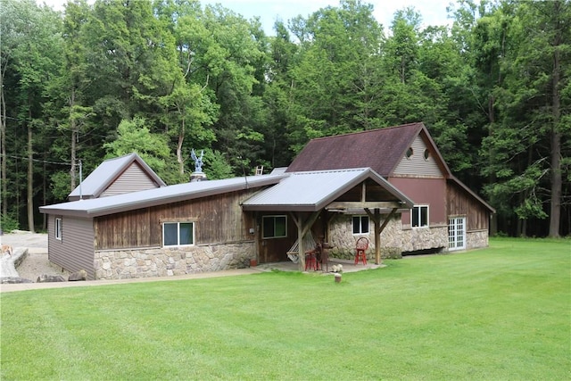 view of front of house featuring stone siding, a front yard, and a patio area
