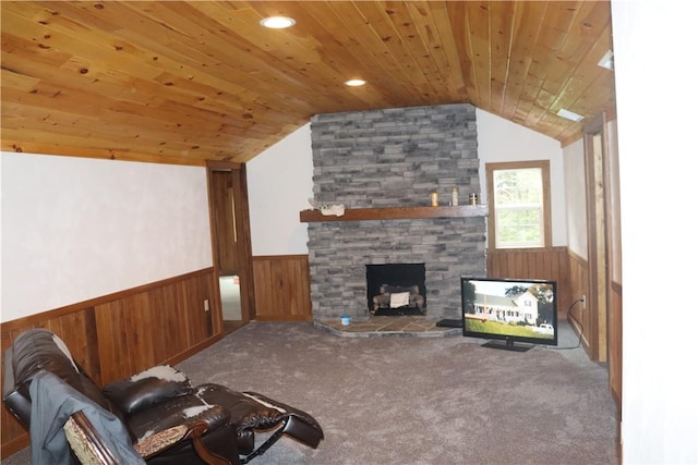 carpeted living room featuring wainscoting, vaulted ceiling, wood ceiling, a fireplace, and wood walls