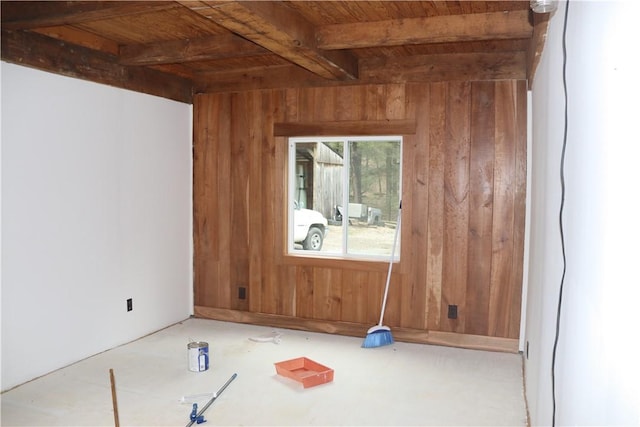 unfurnished room featuring wood walls, wooden ceiling, and beamed ceiling