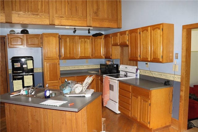 kitchen with black appliances, a sink, brown cabinetry, dark countertops, and dark wood-type flooring
