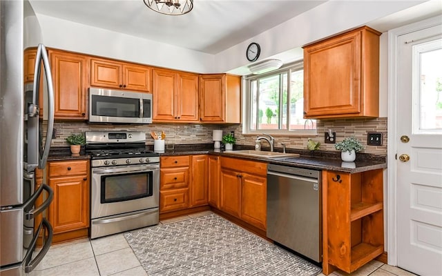 kitchen with stainless steel appliances, a sink, brown cabinets, and light tile patterned floors