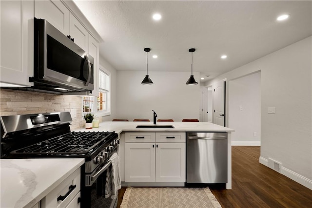 3334 Comanche Rd, Upper St Clair, PA 15241 - kitchen featuring appliances with stainless steel finishes, a sink, a peninsula, decorative backsplash, and white cabinetry
