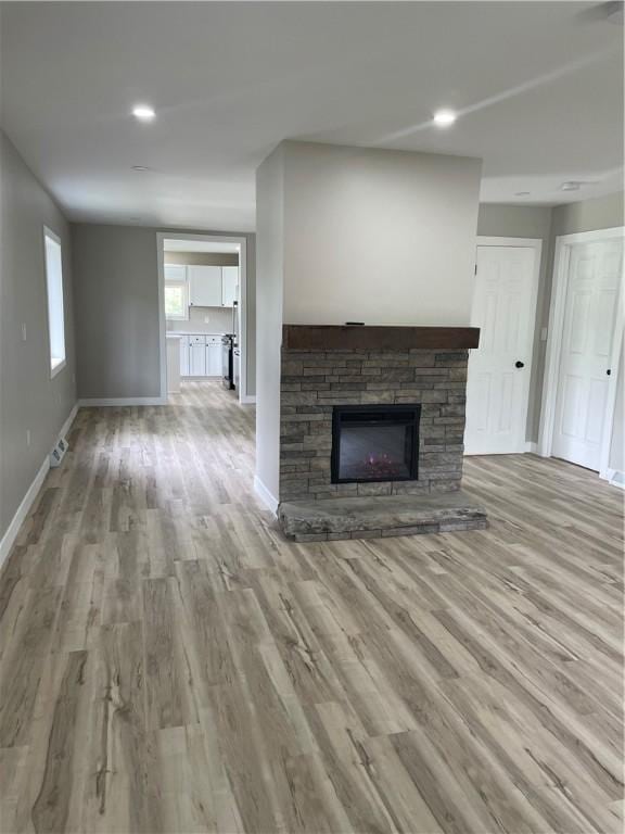 1215 Main St, Bentleyville, PA 15314 - unfurnished living room featuring wood finished floors, baseboards, a stone fireplace, and recessed lighting
