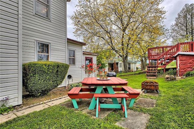 view of grassy yard with an outdoor fire pit, stairs, and outdoor dining area