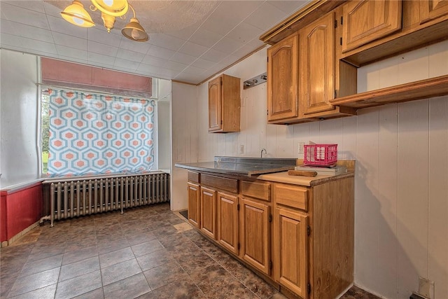 kitchen featuring radiator heating unit, brown cabinets, and wood walls